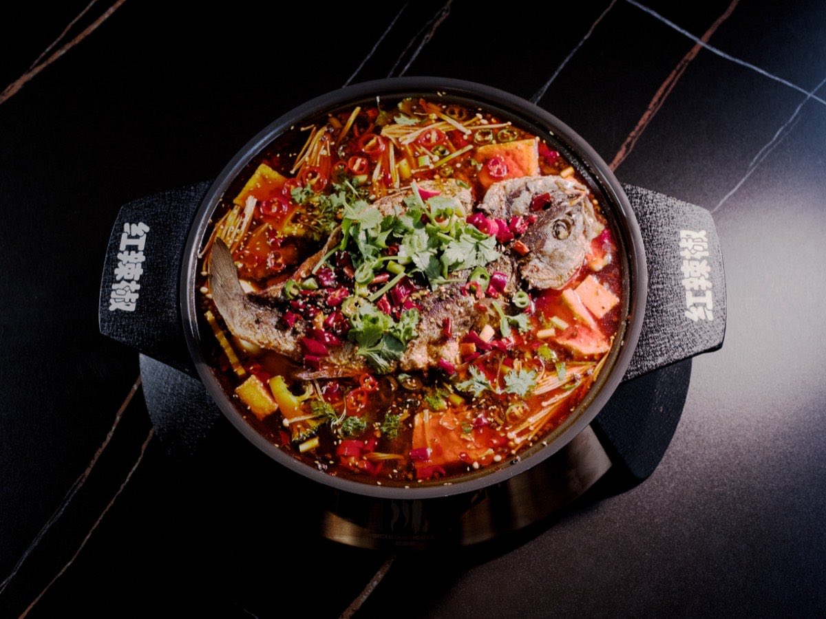 Sichuan House fish hotpot in a branded pot, photographed from above on dark stone